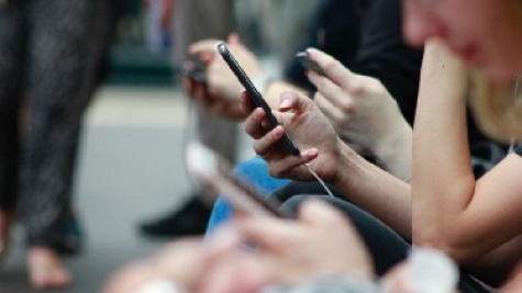 White forearms and hands are seen holding a thin smartphone