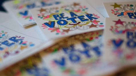 Scattered pile of colorful hand-drawn stickers read "BE A VOTER" over designs and stars