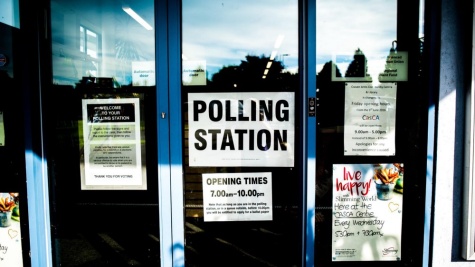 Photograph of an entrance to a polling station. Includes sign with opening times from 7am-10pm.